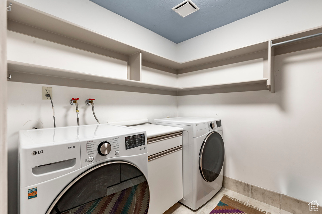 Washroom with hookup for a washing machine, independent washer and dryer, and light tile floors