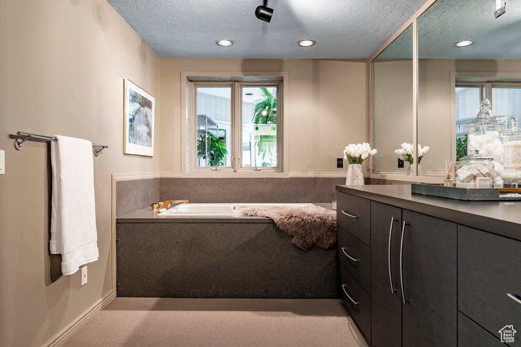 Bathroom with a bathtub, a textured ceiling, and vanity