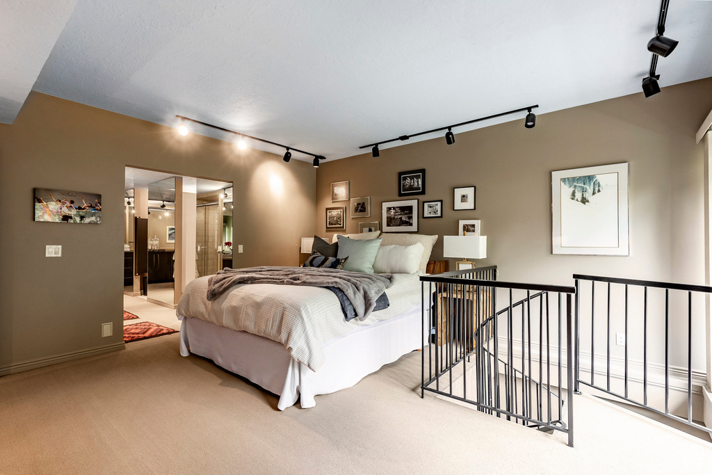 Carpeted bedroom featuring track lighting and connected bathroom