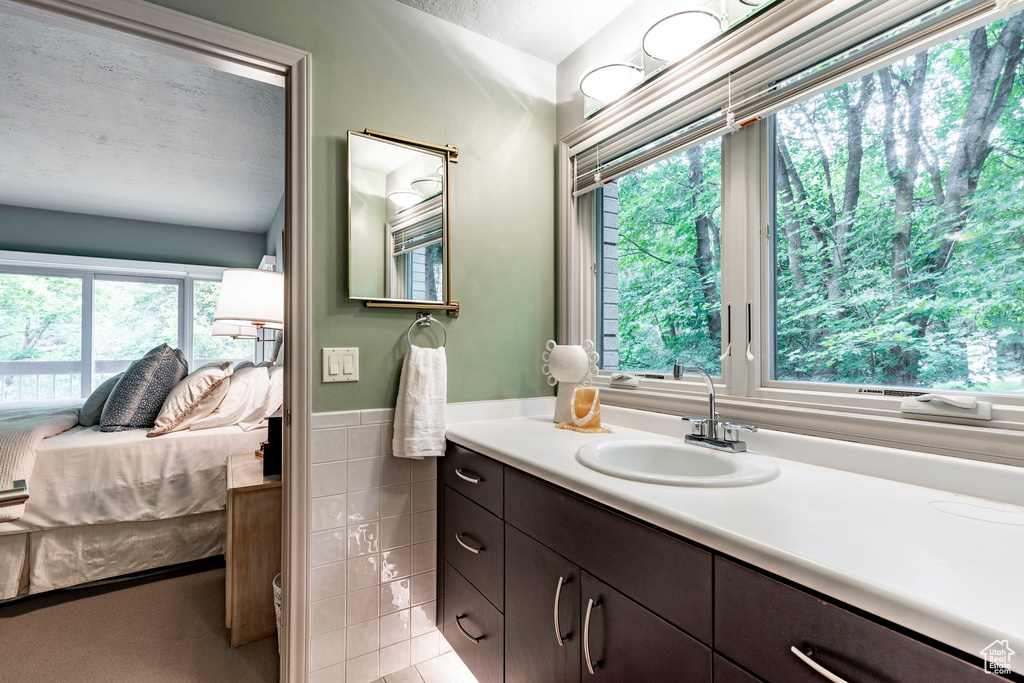 Bathroom featuring a wealth of natural light, vanity with extensive cabinet space, and a textured ceiling