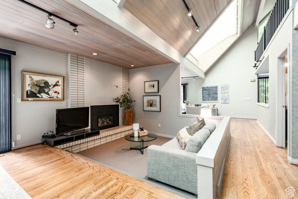 Living room with track lighting, a high ceiling, light hardwood / wood-style floors, and wood ceiling