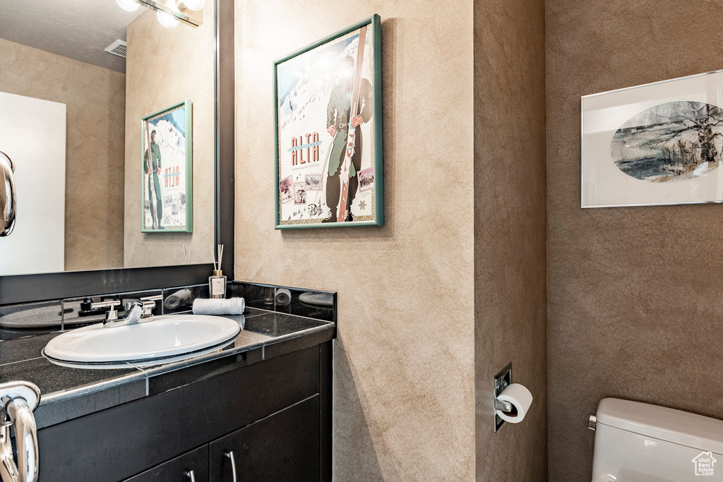 Bathroom with vanity with extensive cabinet space and toilet