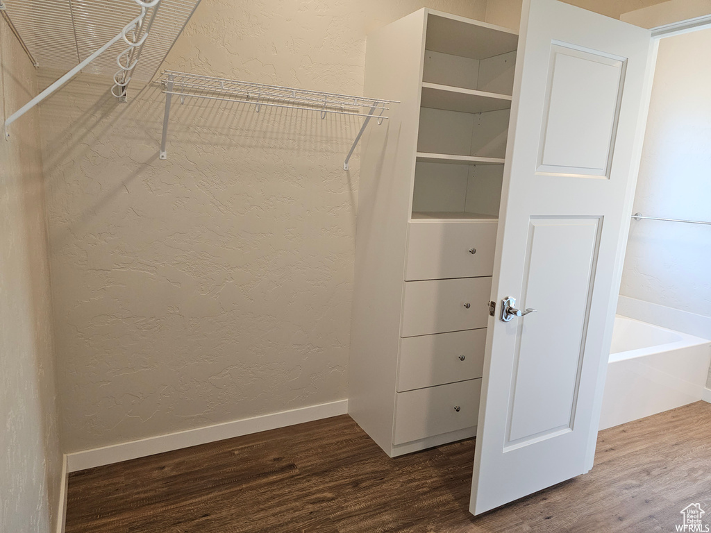 Walk in closet with hardwood / wood-style flooring