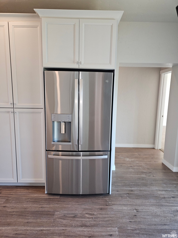 Kitchen featuring stainless steel fridge with ice dispenser, white cabinets, and wood-type flooring