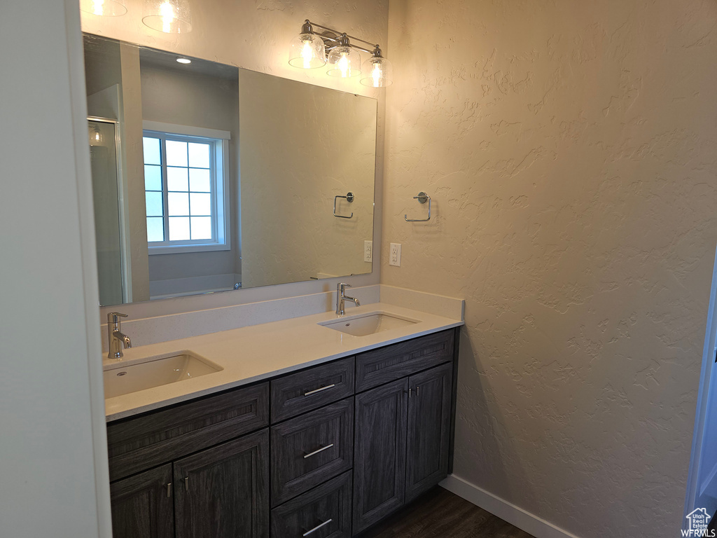 Bathroom featuring vanity with extensive cabinet space, double sink, and hardwood / wood-style flooring