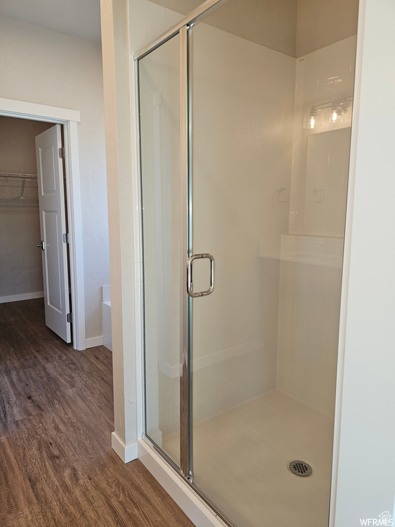 Bathroom featuring a shower with door and wood-type flooring