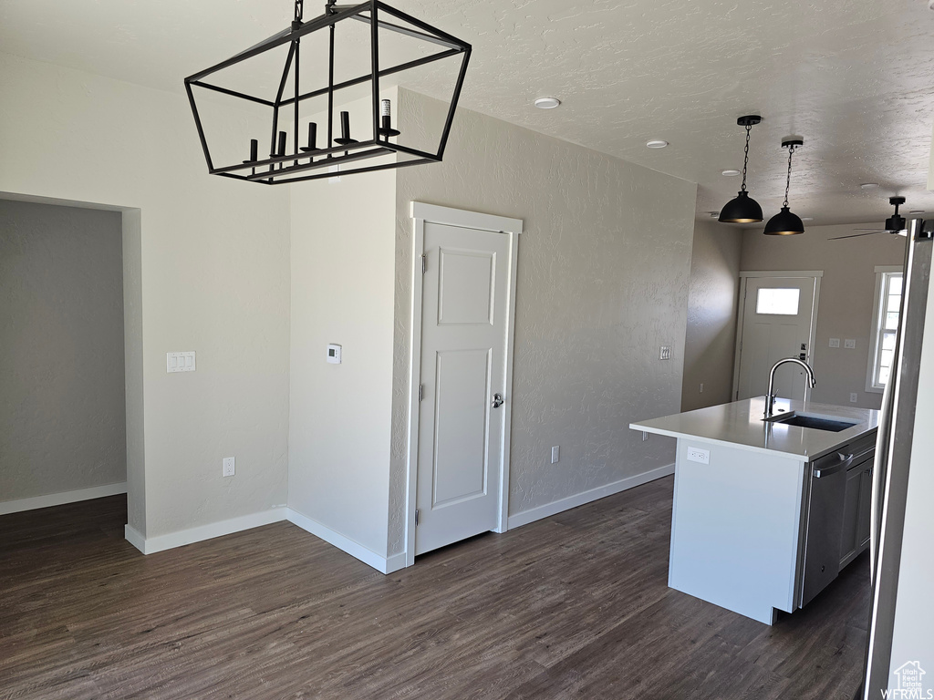 Kitchen featuring an island with sink, dishwasher, dark hardwood / wood-style flooring, hanging light fixtures, and sink