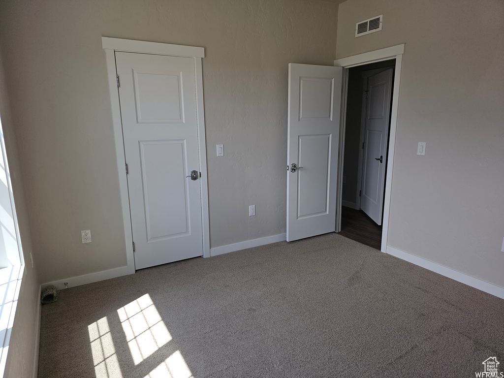 Unfurnished bedroom with dark carpet