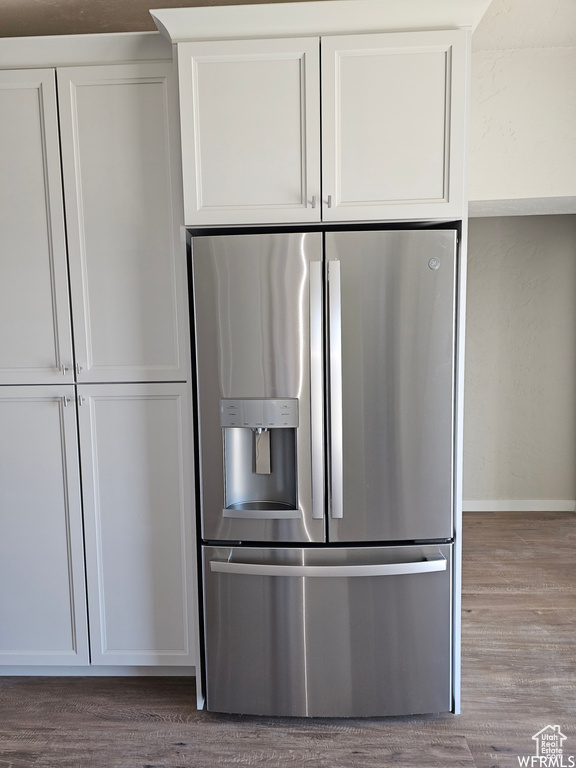 Kitchen with stainless steel fridge, white cabinets, and dark wood-type flooring