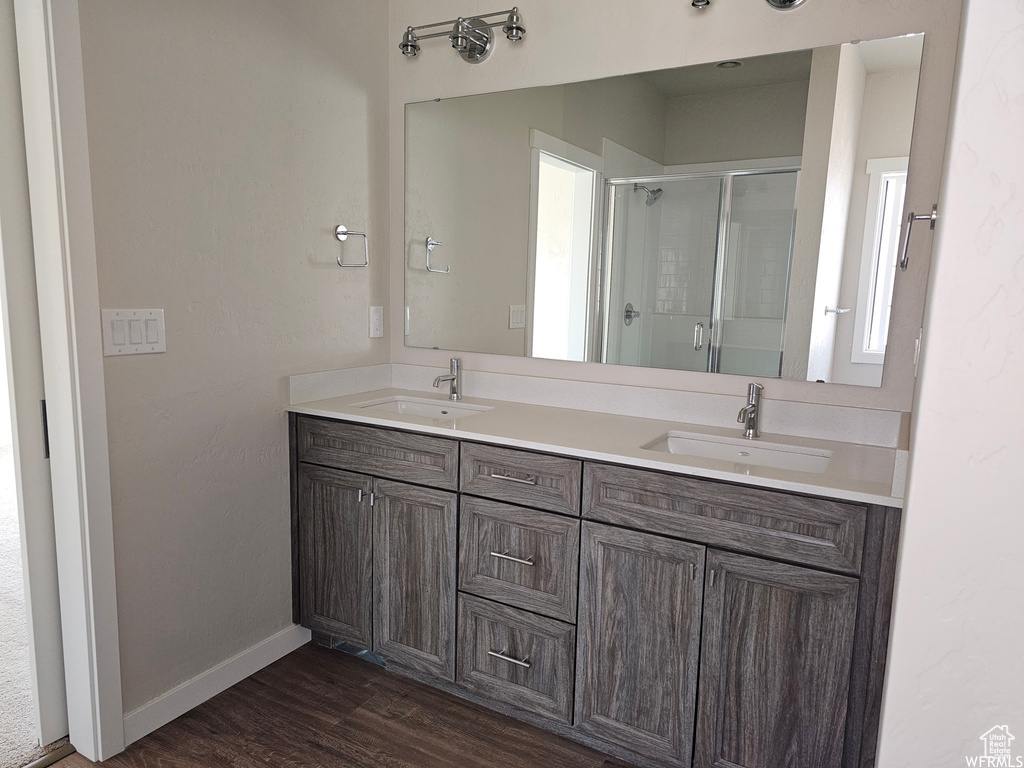 Bathroom with walk in shower, double sink vanity, and hardwood / wood-style floors