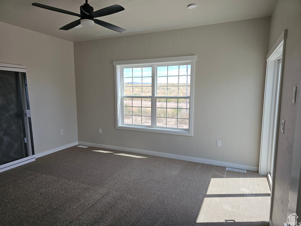 Carpeted spare room featuring ceiling fan