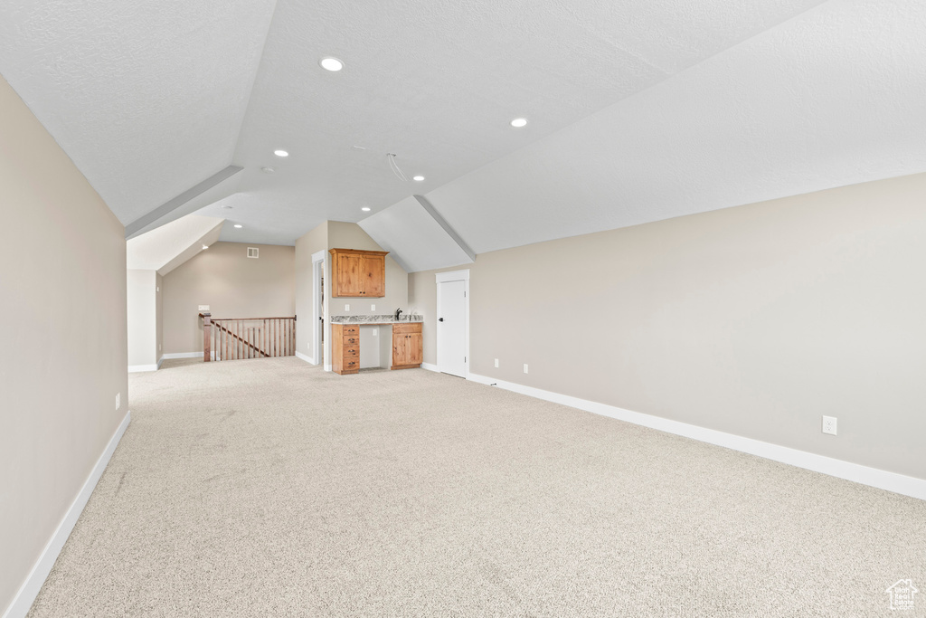 Unfurnished living room featuring carpet flooring and lofted ceiling