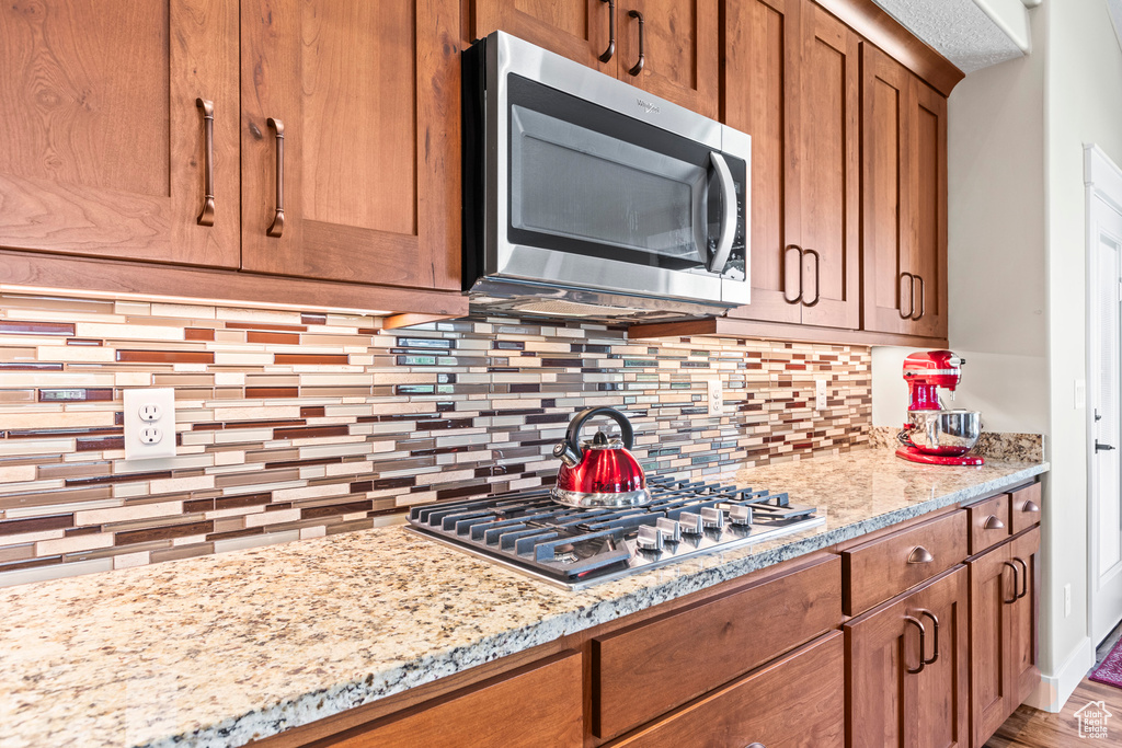 Kitchen with stainless steel appliances, light stone counters, and backsplash