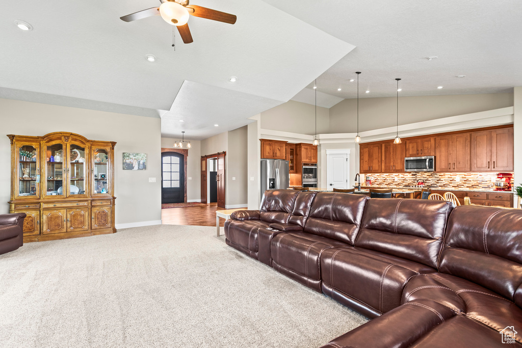 Living room with light carpet, high vaulted ceiling, sink, and ceiling fan