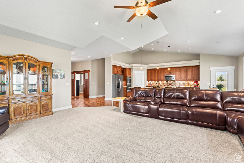 Living room with vaulted ceiling, light carpet, and ceiling fan