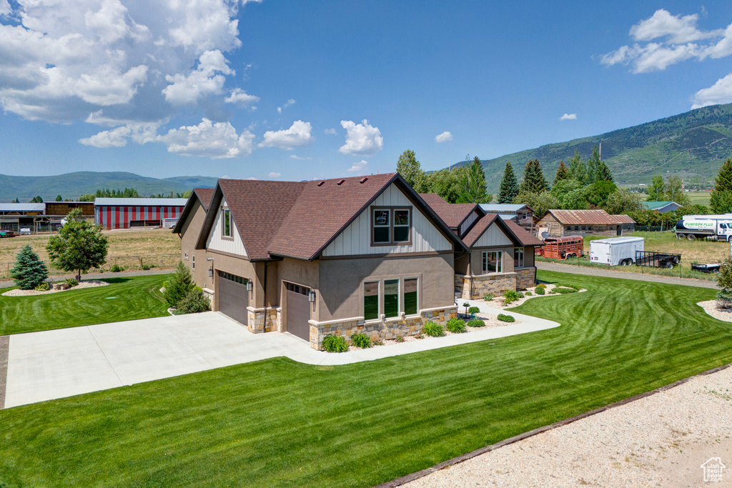 View of front of property with a garage, a front yard, and a mountain view