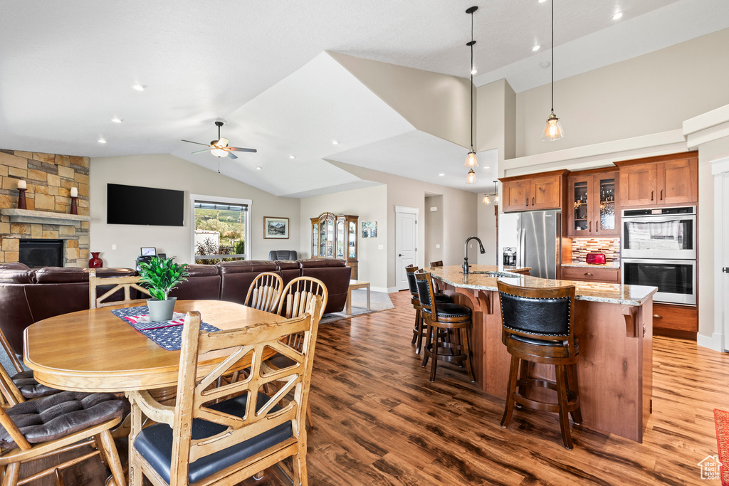 Dining area featuring ceiling fan, dark hardwood / wood-style flooring, a fireplace, and vaulted ceiling