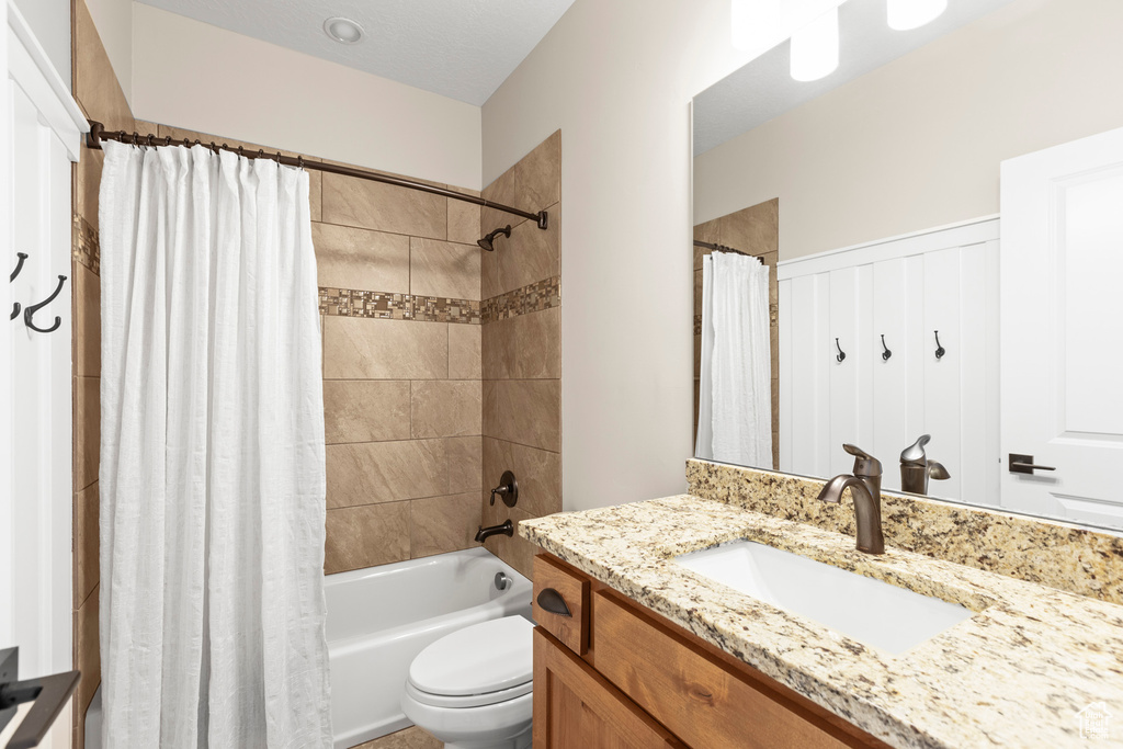 Full bathroom with shower / bathtub combination with curtain, vanity, and toilet