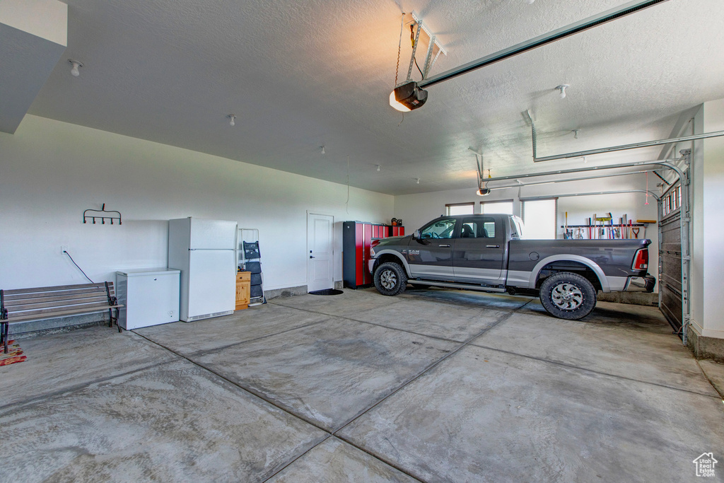 Garage featuring a garage door opener and white fridge