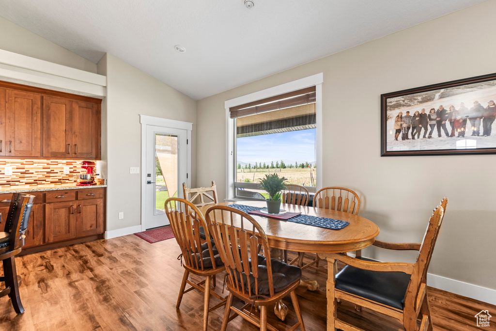 Dining area with lofted ceiling, plenty of natural light, and light wood-type flooring