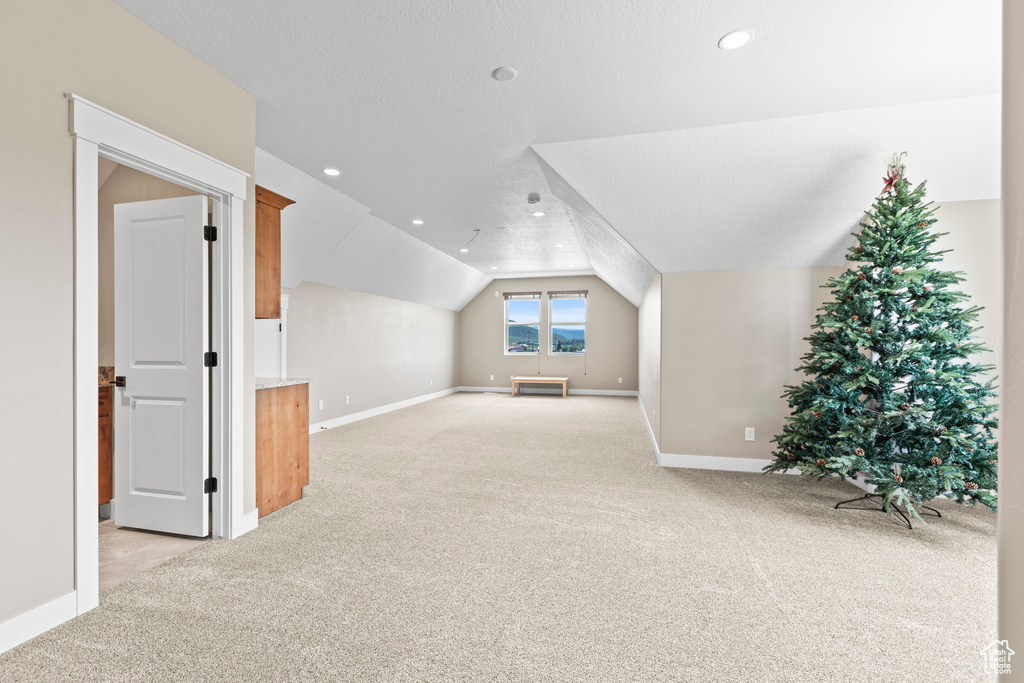 Additional living space with light colored carpet and lofted ceiling