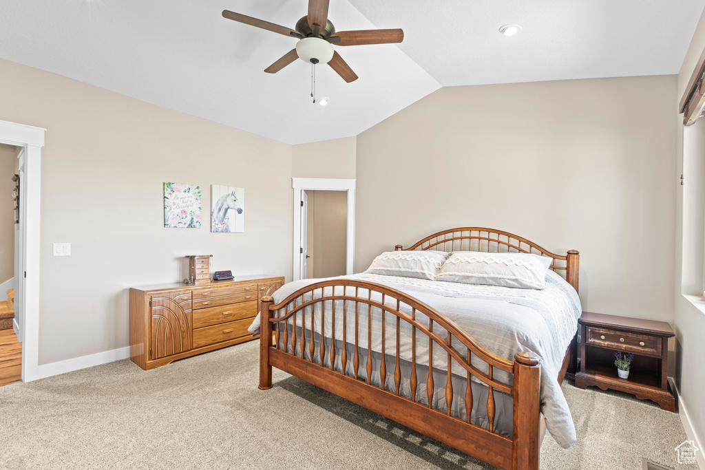 Carpeted bedroom featuring ceiling fan and vaulted ceiling