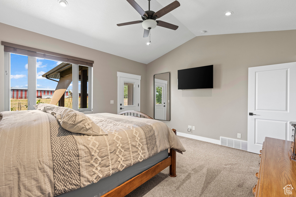 Carpeted bedroom featuring ceiling fan and vaulted ceiling