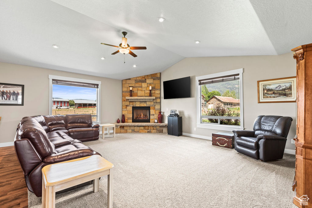 Living room featuring lofted ceiling, carpet, ceiling fan, and a fireplace