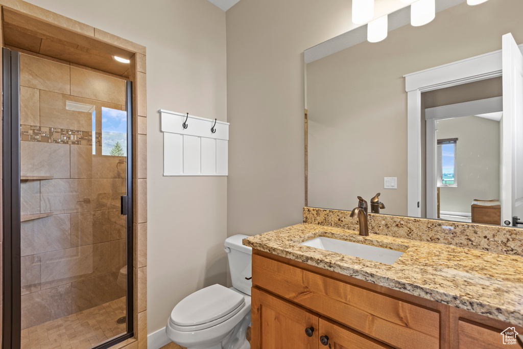 Bathroom featuring a shower with door, a healthy amount of sunlight, toilet, and vanity