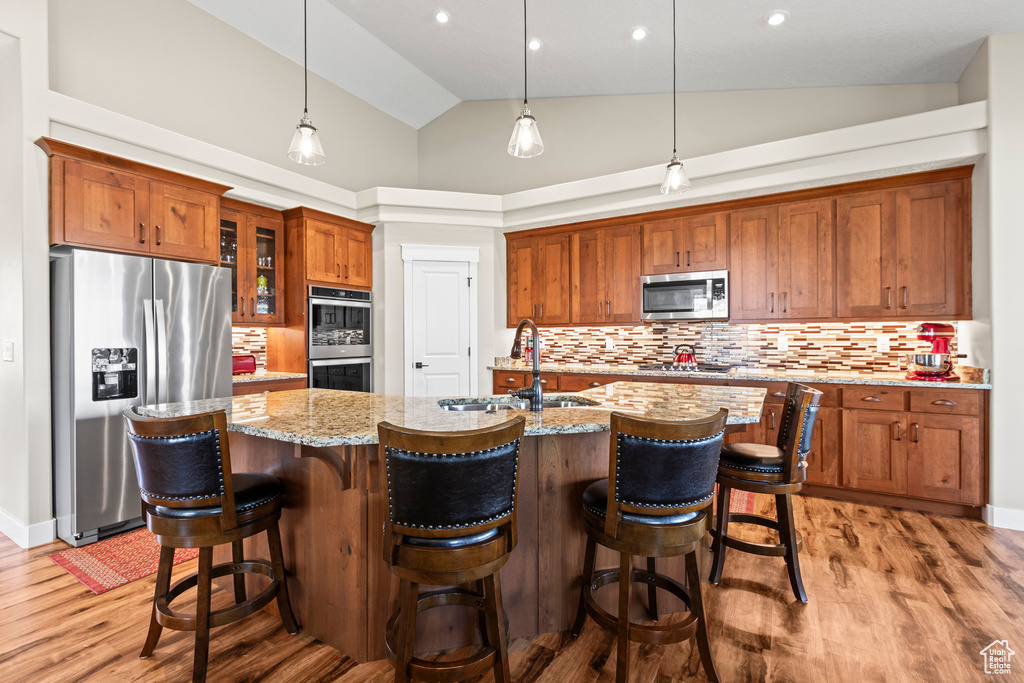 Kitchen with appliances with stainless steel finishes, decorative light fixtures, sink, and tasteful backsplash