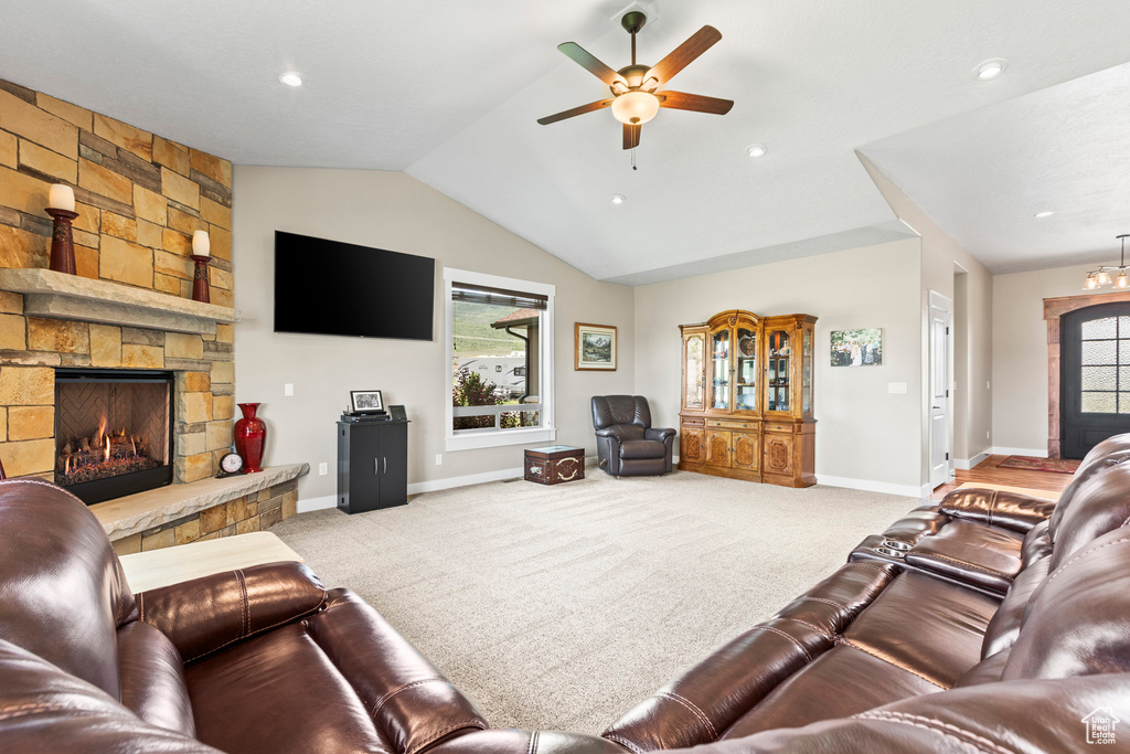 Living room with ceiling fan, light carpet, a fireplace, a healthy amount of sunlight, and lofted ceiling