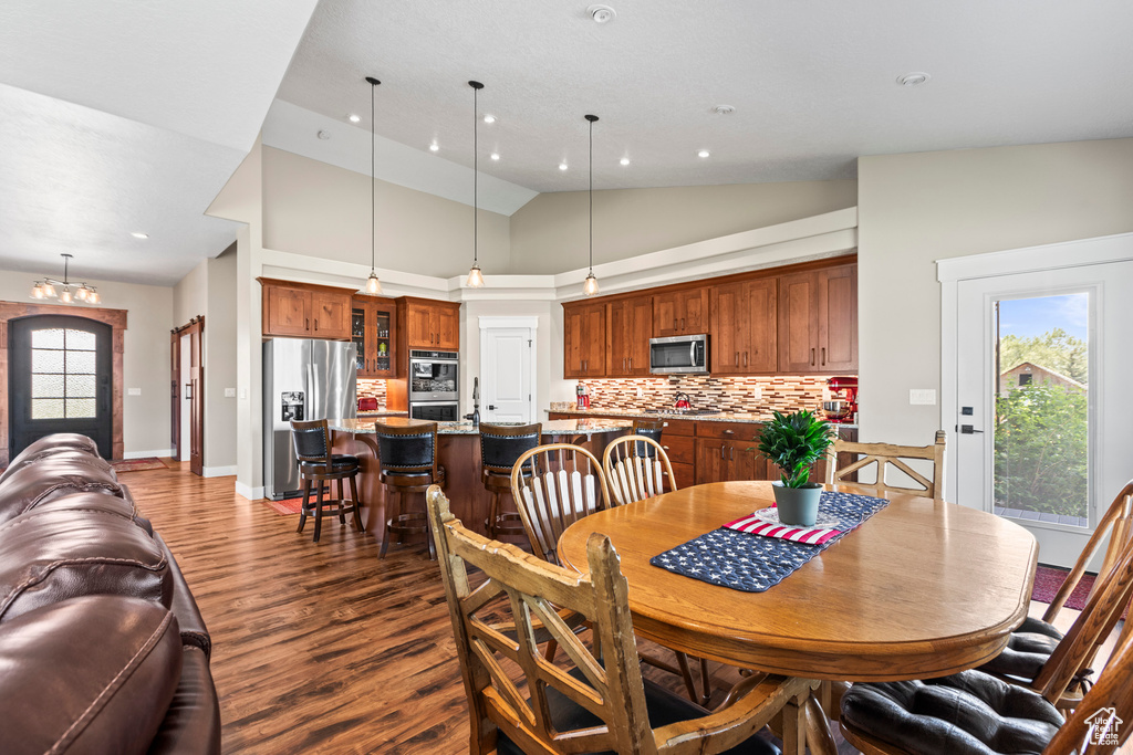 Dining space with high vaulted ceiling, a notable chandelier, and hardwood / wood-style floors