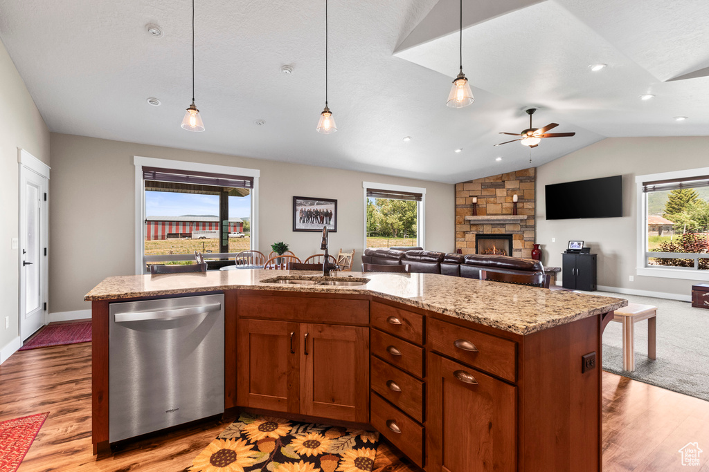 Kitchen featuring a stone fireplace, decorative light fixtures, sink, and stainless steel dishwasher