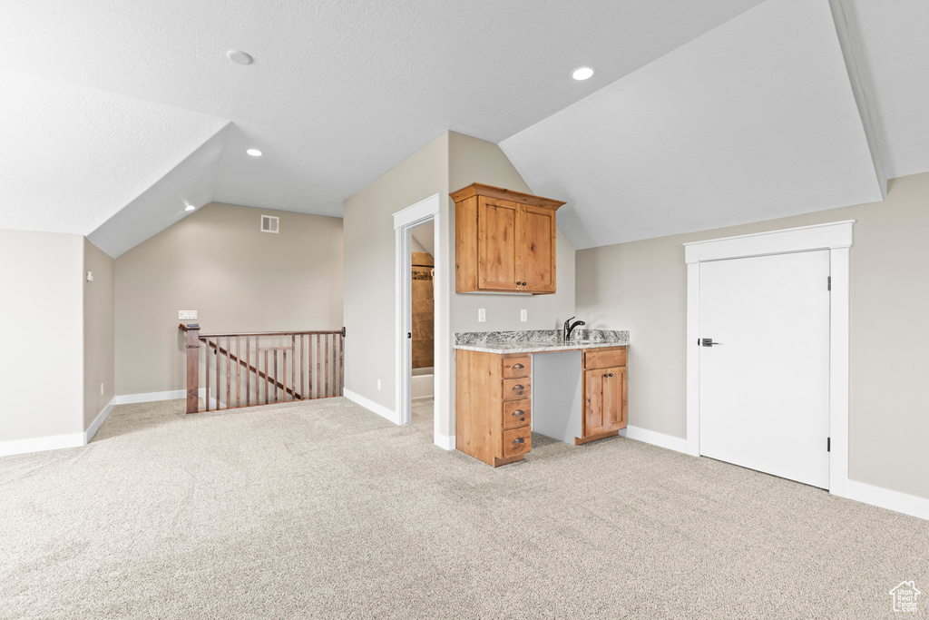 Kitchen featuring light carpet, sink, and lofted ceiling