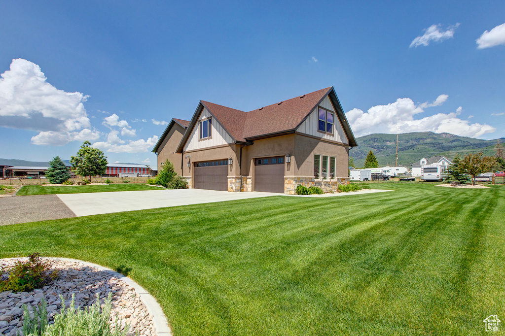 View of front of house featuring a garage, a mountain view, and a front lawn