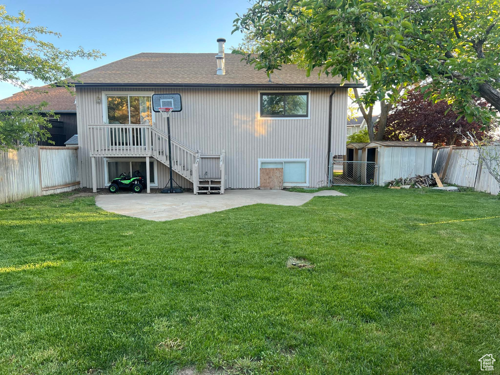 Rear view of property with a storage shed, a patio area, and a lawn