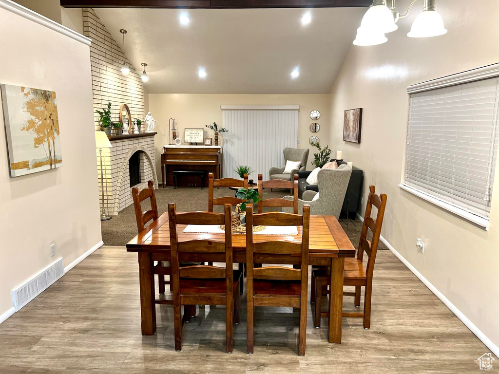 Dining area featuring a brick fireplace, vaulted ceiling, and hardwood / wood-style floors