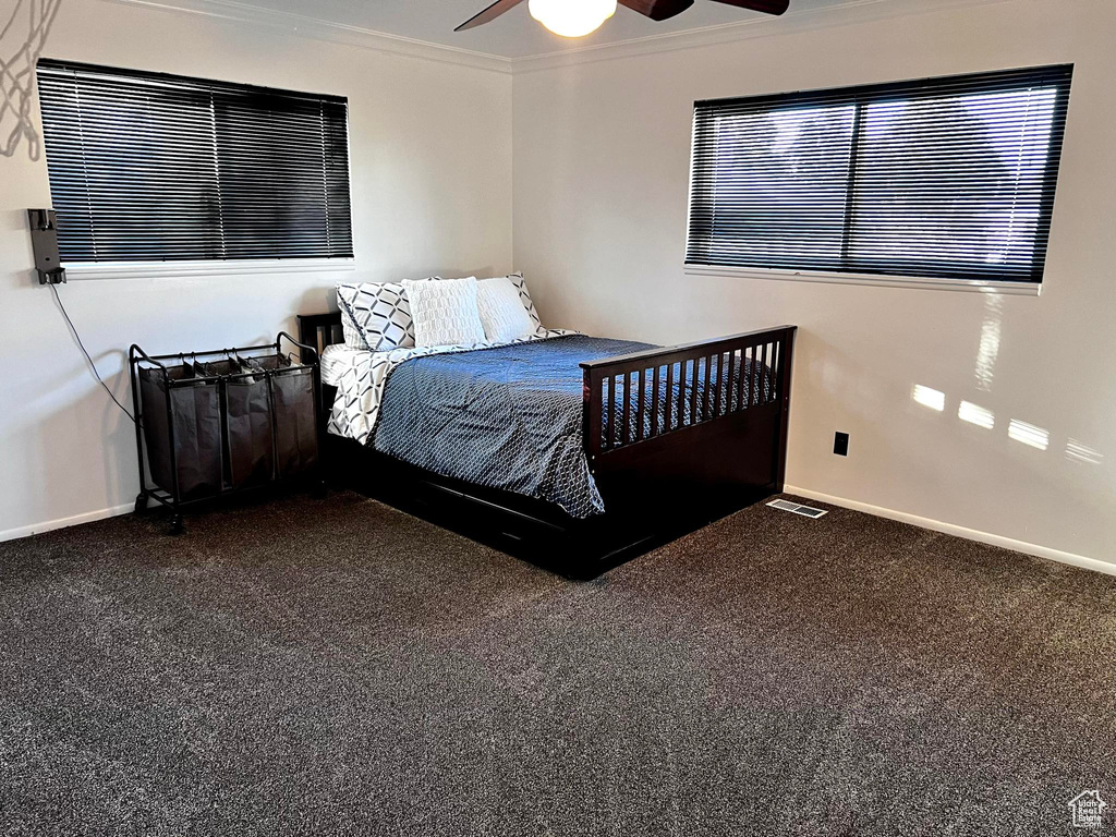 Carpeted bedroom with ornamental molding and ceiling fan