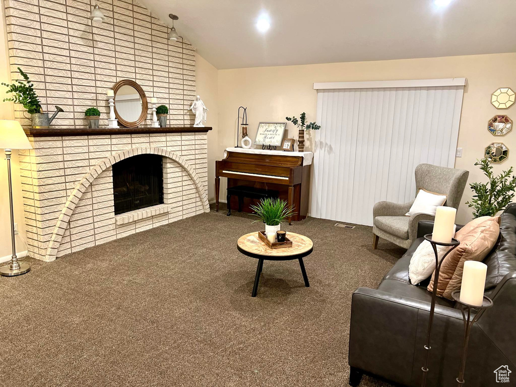 Carpeted living room with vaulted ceiling and a fireplace