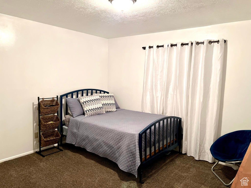 Bedroom with a textured ceiling and dark carpet