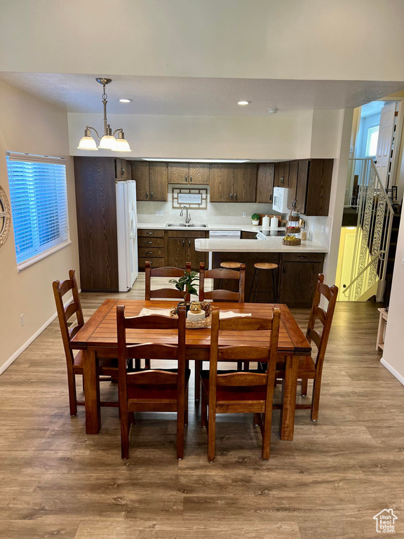 Dining area with sink, hardwood / wood-style flooring, and an inviting chandelier