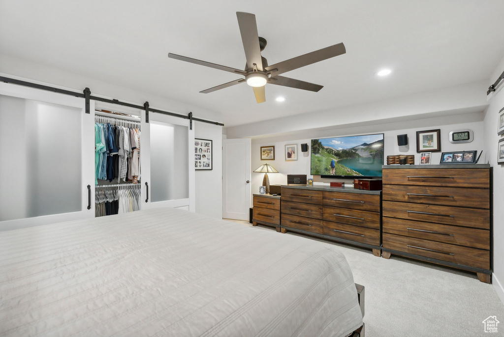 Bedroom featuring a barn door, a closet, carpet floors, and ceiling fan