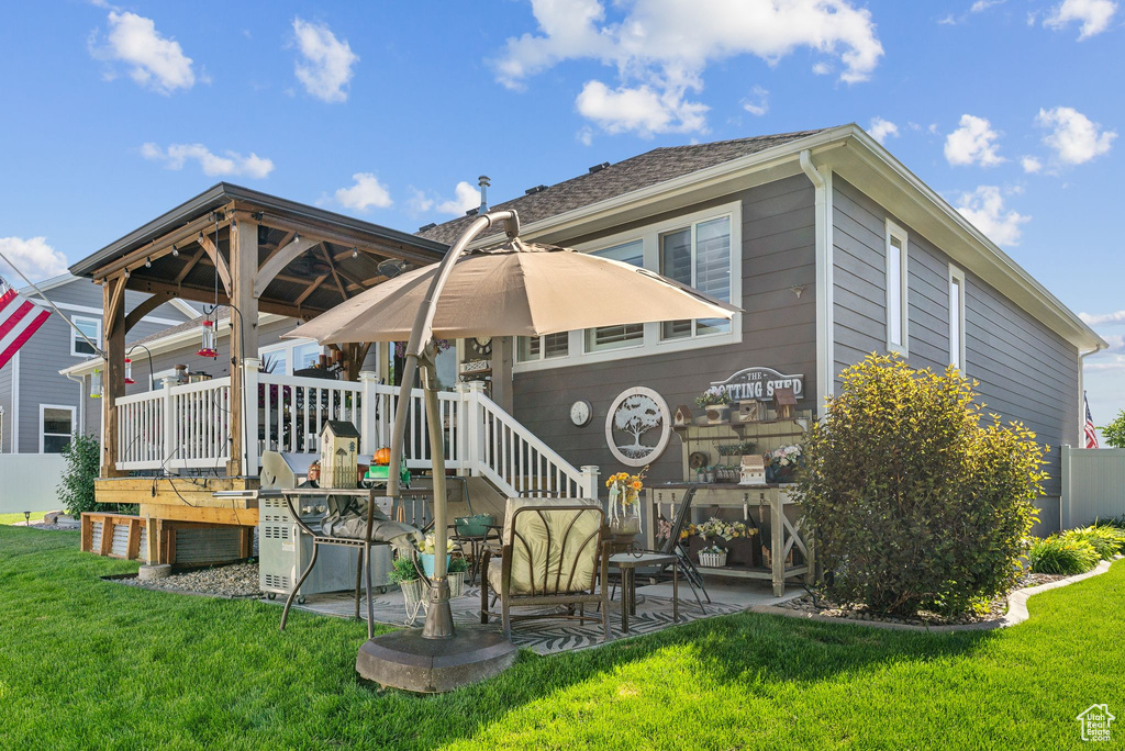 Back of house featuring a deck, a lawn, and a patio area