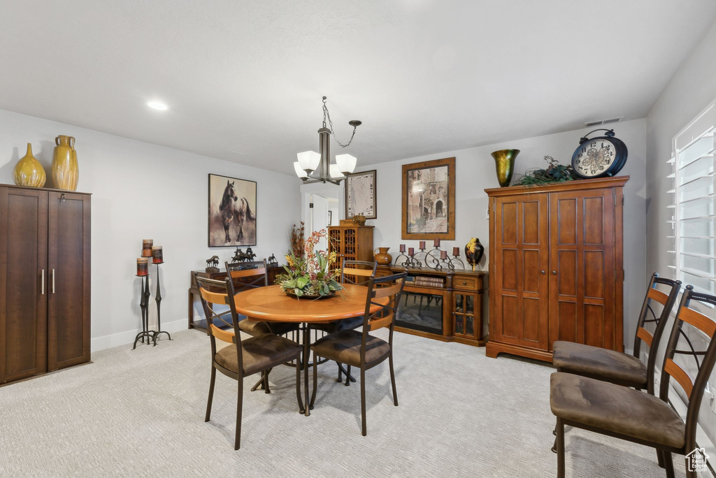 Carpeted dining space featuring an inviting chandelier