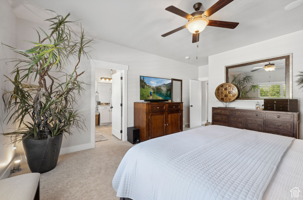 Bedroom featuring light carpet, ensuite bathroom, and ceiling fan