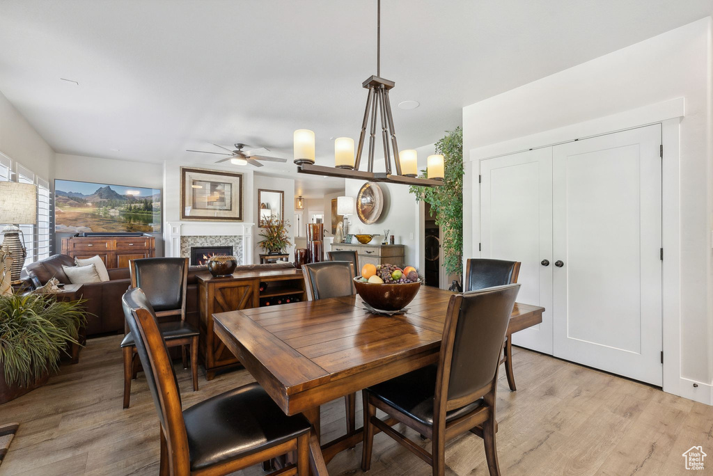 Dining space featuring light wood-type flooring and ceiling fan with notable chandelier