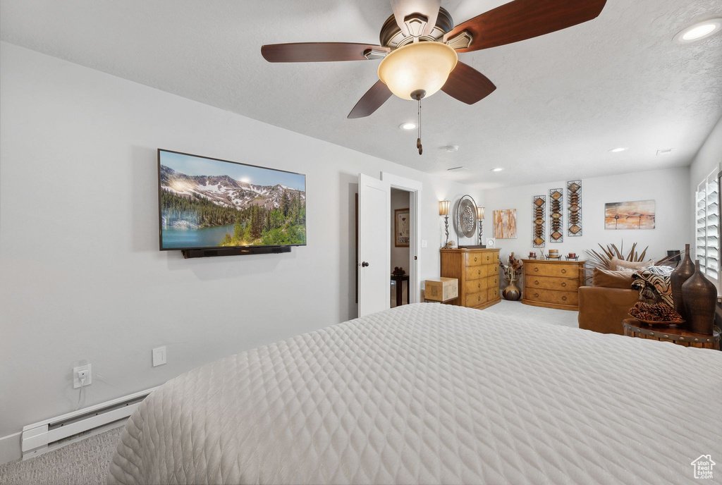 Carpeted bedroom with ceiling fan and baseboard heating