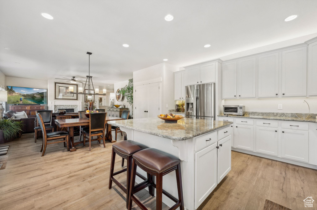 Kitchen featuring a center island, white cabinetry, stainless steel fridge, and light hardwood / wood-style flooring