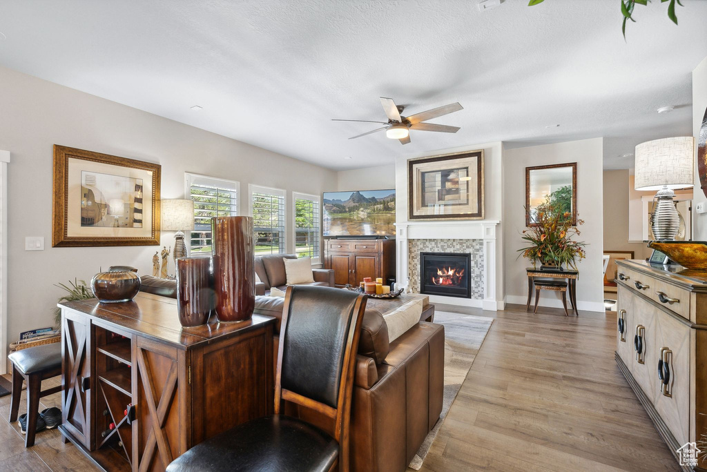 Living room with ceiling fan, light hardwood / wood-style flooring, and a tile fireplace