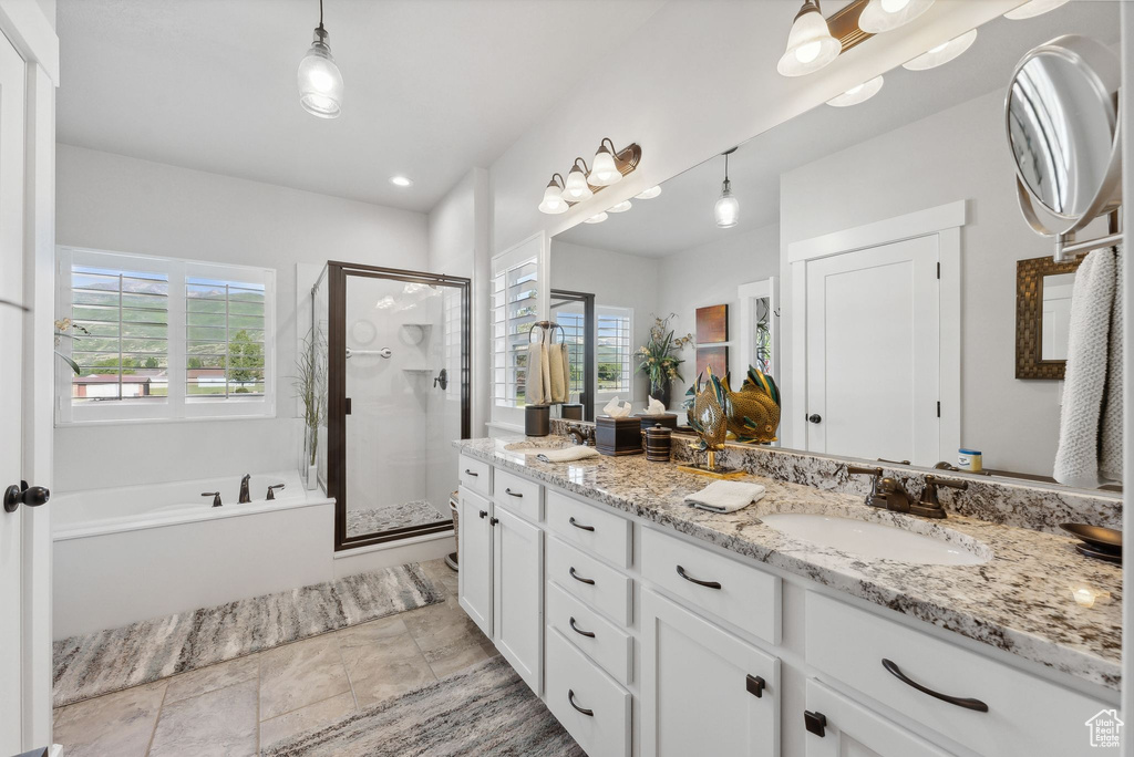 Bathroom featuring tile floors, dual sinks, shower with separate bathtub, and vanity with extensive cabinet space